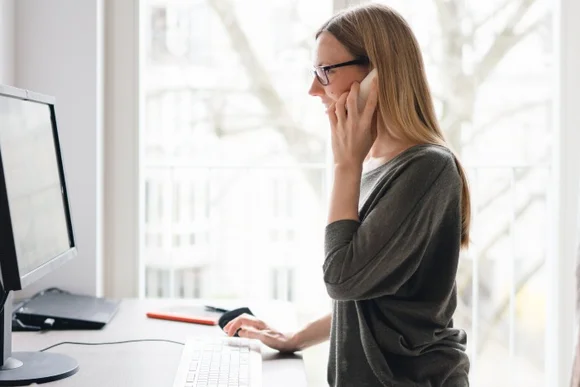 Person telefoniert am Computer.